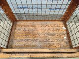 a metal cage with a rusted bottom and a sign on it