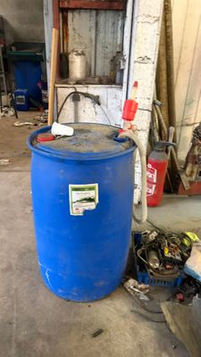 un fût bleu posé dans un garage à côté d'une poubelle bleue