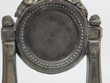 a silver clock that is on a stand on a table