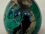 une boule verte et noire sur laquelle est représentée une main
