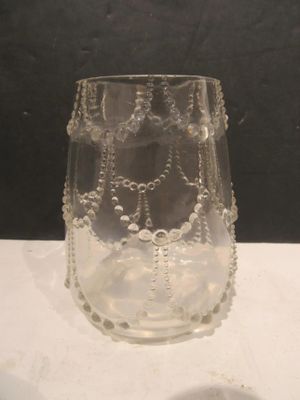 a glass vase with beads on it sitting on a table