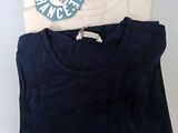 two t - shirts are sitting on a table with a blue and white tag
