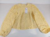 La chemise est jaune et porte une étiquette blanche.