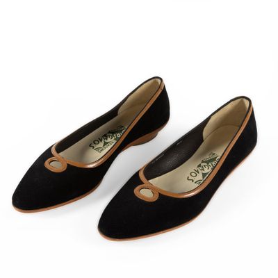 a pair of black sued shoes with brown trims on a white background