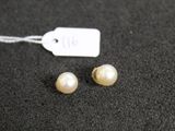 a pair of pearl earrings on a black surface with a price tag