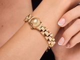 woman wearing a gold bracelet and a gold watch on her wrist