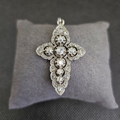un gros plan d'une croix en diamant posée sur un coussin, sur une table