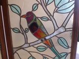 un oiseau en vitrail assis sur une branche d'arbre
