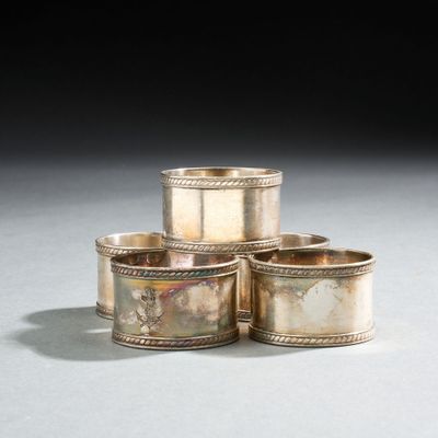 Trois coupes en argent sont posées sur une table devant un fond noir.