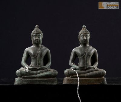 deux statues de bouddhas assis sur une surface noire