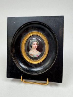 un portrait miniature représentant une femme, dans un cadre noir et doré