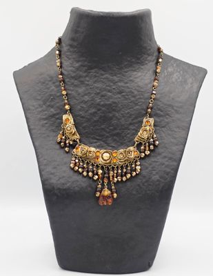 un collier avec un mannequin noir orné de perles dorées et marron