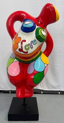 un vase coloré posé sur un socle noir, avec un mur blanc en arrière-plan