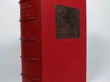 a red book sitting on top of a white table next to a white wall
