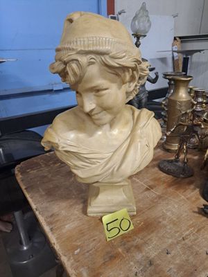 un buste représentant un garçon coiffé d'un chapeau, posé sur une table