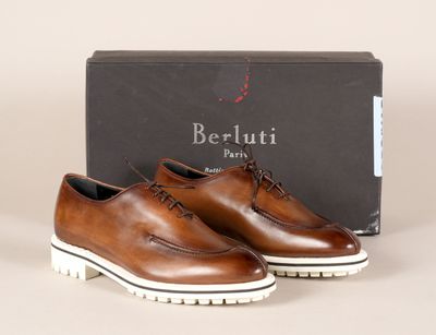 une paire de chaussures marron à semelles blanches posée devant une boîte
