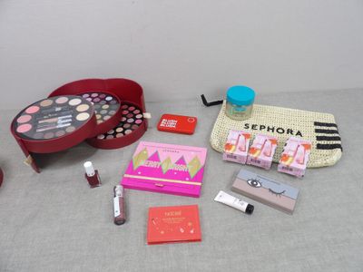 une table sur laquelle sont posés du maquillage, un rouge à lèvres, un étui à rouge à lèvres et d'autres objets