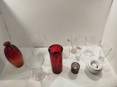 de nombreux verres à vin posés sur une table, avec un vase rouge