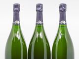 trois bouteilles de vin posées les unes à côté des autres sur une surface blanche
