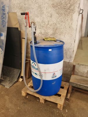 un fût bleu posé sur une palette, auquel est raccordé un tuyau