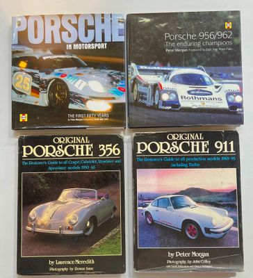 three porsche books on a white surface
