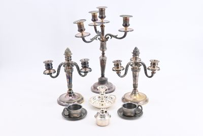 trois chandeliers en argent sont posés sur une surface blanche