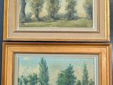 Deux tableaux représentant des arbres sont accrochés au mur d'une pièce.