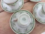four tea cups and saucers are sitting on a wooden table