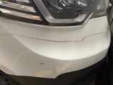 une voiture blanche cabossée, garée sur un parking