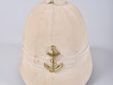 an old hat with a gold anchor on it sitting on a white surface