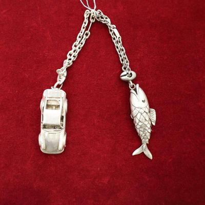 une voiture en argent et un pendentif en forme de poisson suspendu à une chaîne