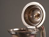 a silver coffee pot with a handle on a table