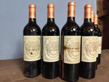 six bottles of wine are lined up on a wooden table