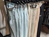 several pairs of pants hanging on a rack in a clothing store