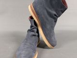 a pair of grey sued boots with brown soles on a grey background