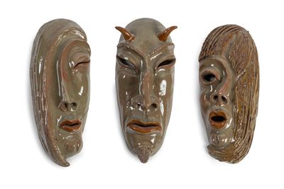 trois masques en céramique posés sur une surface blanche, sur fond blanc