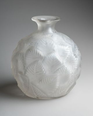 un vase en verre blanc orné d'un motif de feuilles