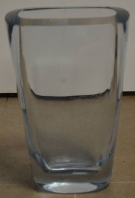 un vase en verre transparent avec un couvercle blanc posé sur une table