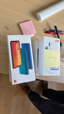 une personne assise à une table avec une boîte de stylos et un téléphone portable