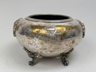 une casserole argentée munie d'une poignée, posée sur une surface blanche