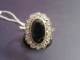 an image of a ring with a large black stone surrounded by small white diamonds