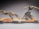 statue of a woman and two dogs running on a marble base