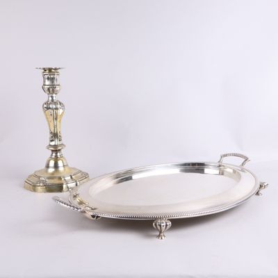 un plateau en argent avec une bougie et une assiette en argent posés sur une table