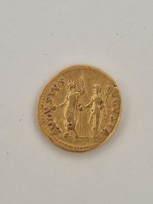 une vieille pièce d'or posée sur une surface blanche, sur laquelle figurent les portraits d'un homme et d'une femme