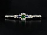 a close up of a diamond and emerald ring on a black surface
