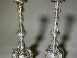 pair of silver candlesticks on a table with a gray background