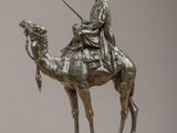 bronze statue of a man riding a camel with a spear in his hand