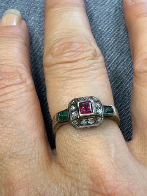 la main d'une femme portant une bague sertie d'un diamant et d'une émeraude