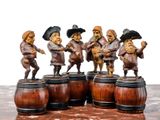 five figurines of men playing a game on a wooden barrel