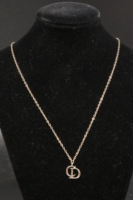a gold necklace with an anchor on a mannequin neck